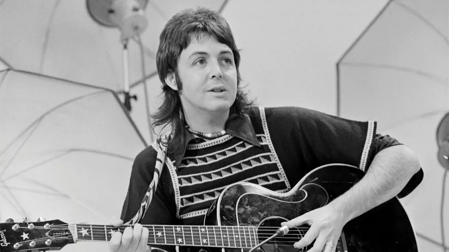 Paul McCartney mit langem Haar und einer Gitarre